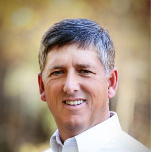 Man wearing a light-colored shirt with a blurred natural background